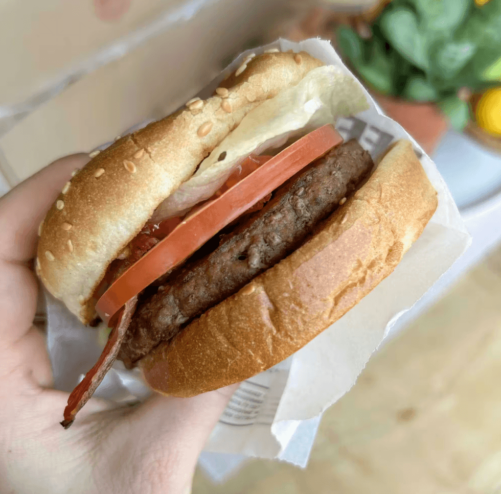A person holding a burger.