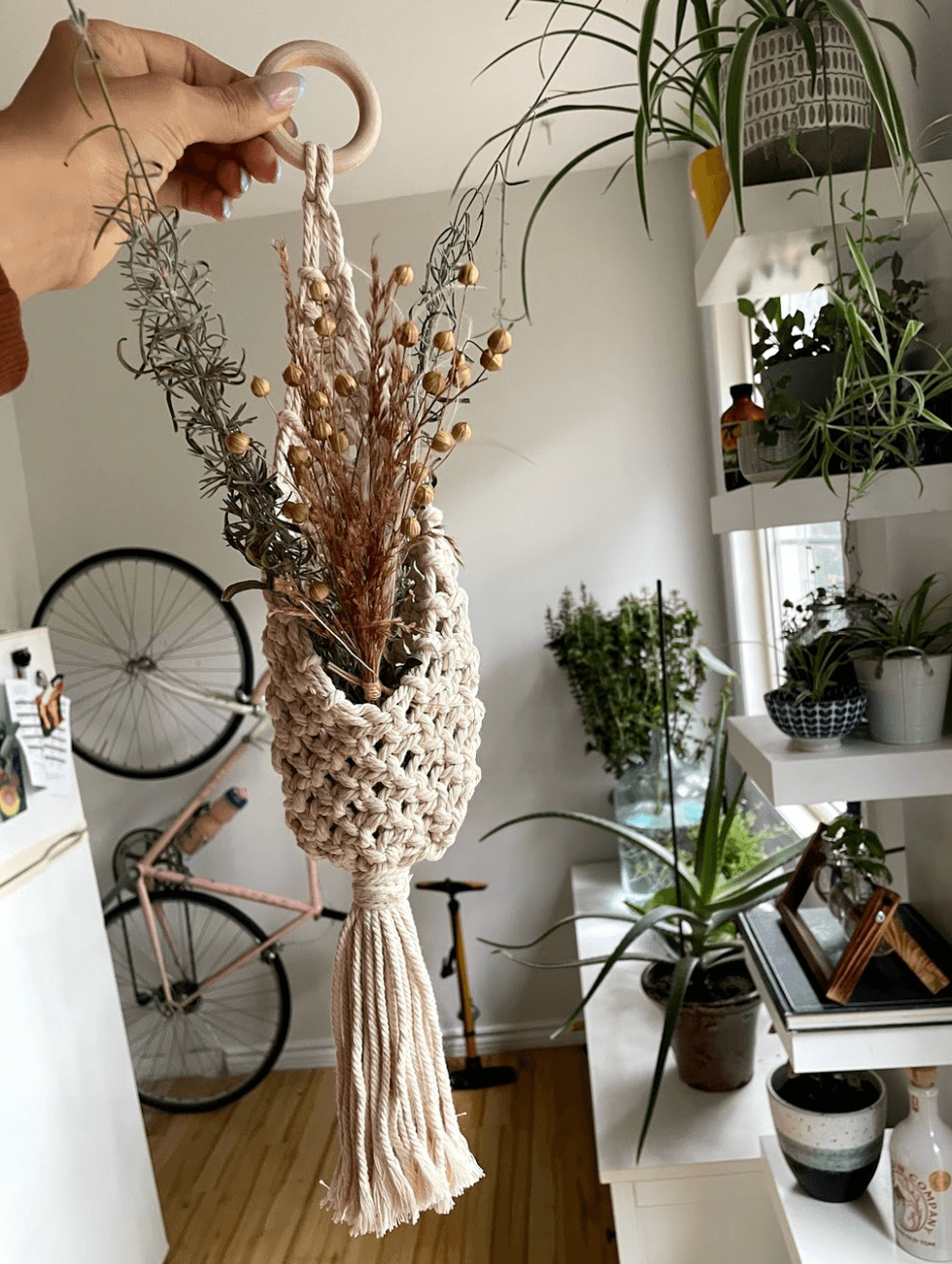 a person holding a dried bouquet of flowers in front of plants and a bike.