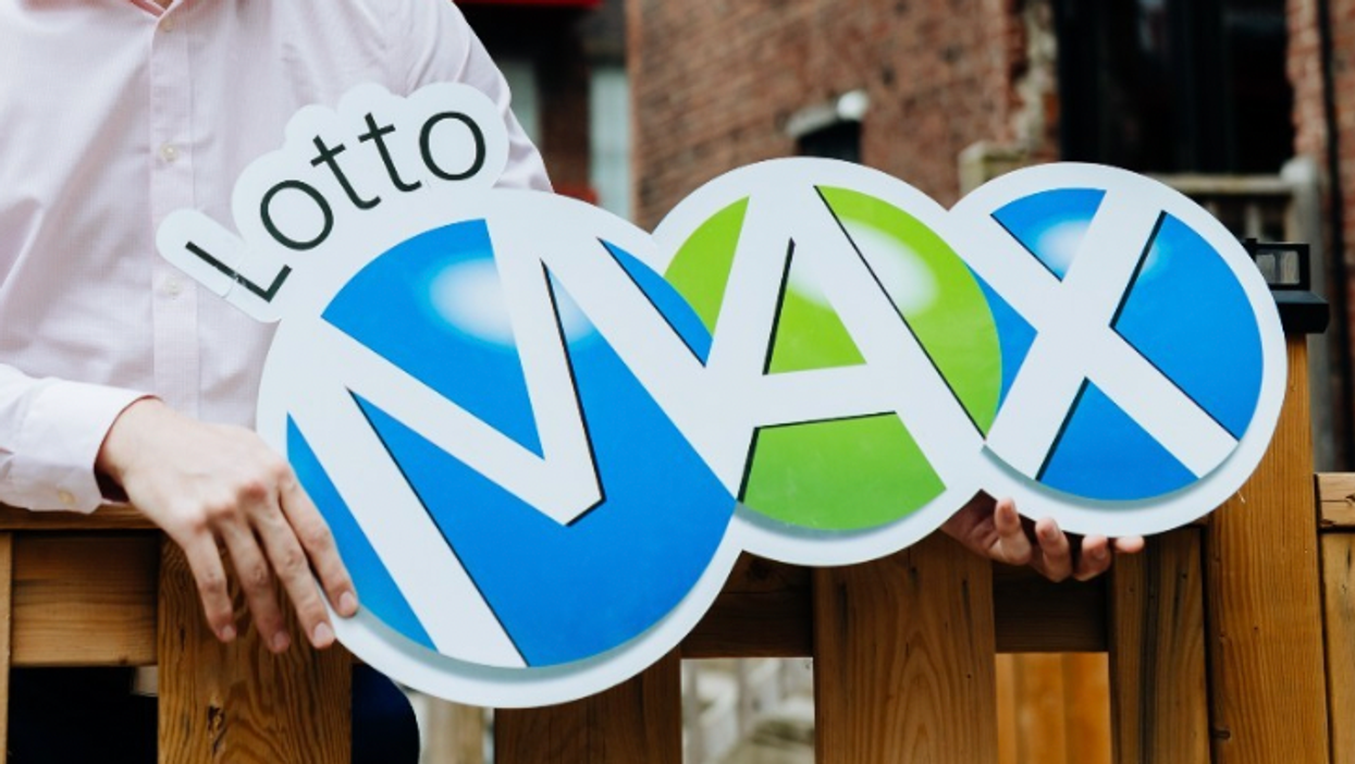 A person holding a Lotto Max sign.