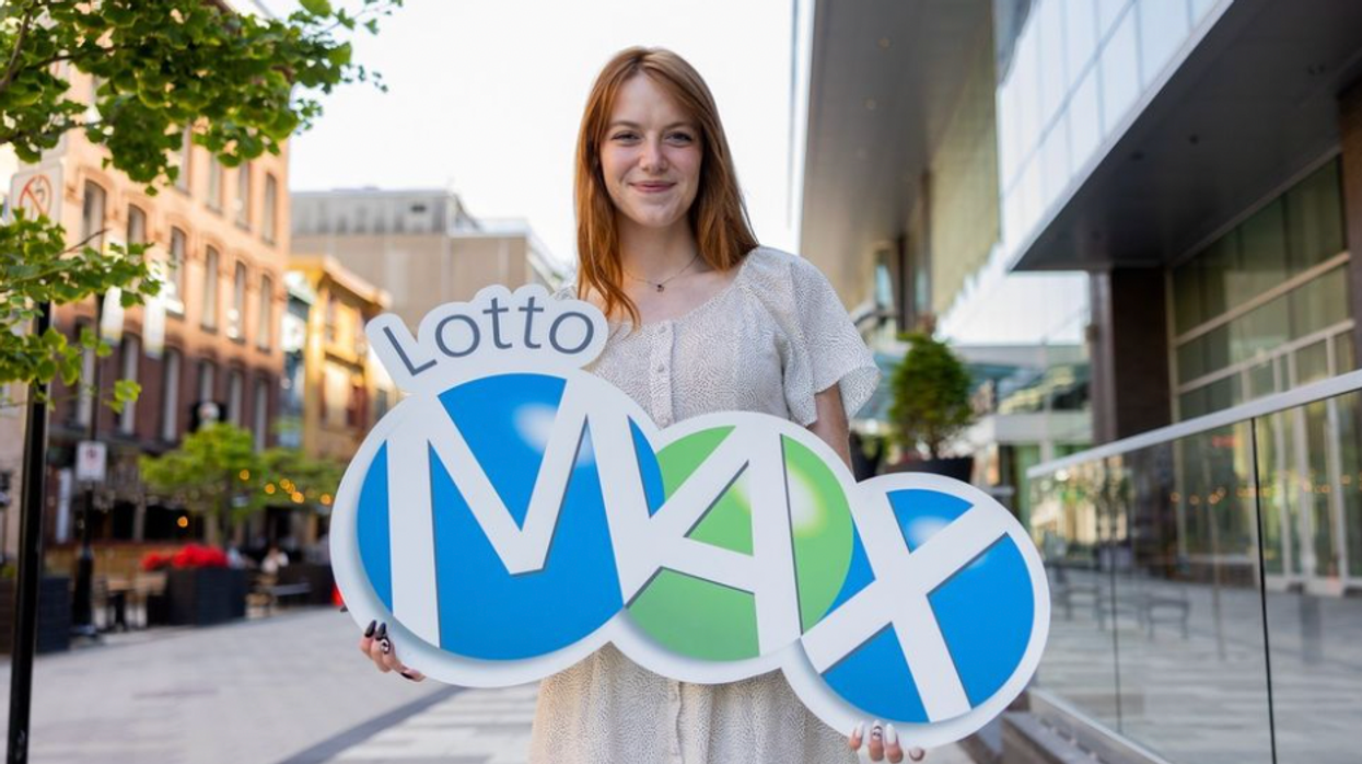A person holding a Lotto Max sign.