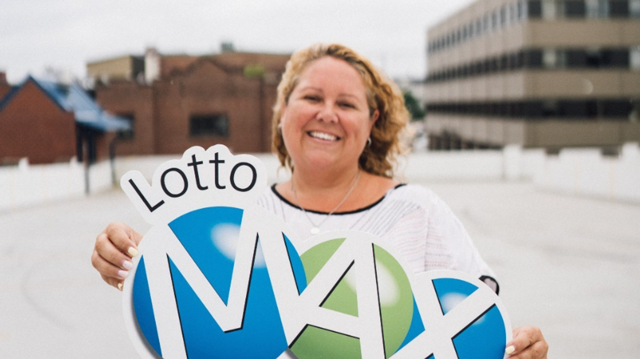 A person holding a Lotto Max sign.