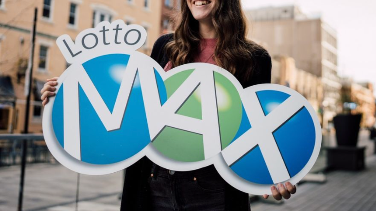 A person holding a Lotto Max sign.