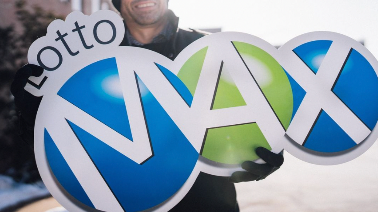 A person holding a Lotto Max sign.