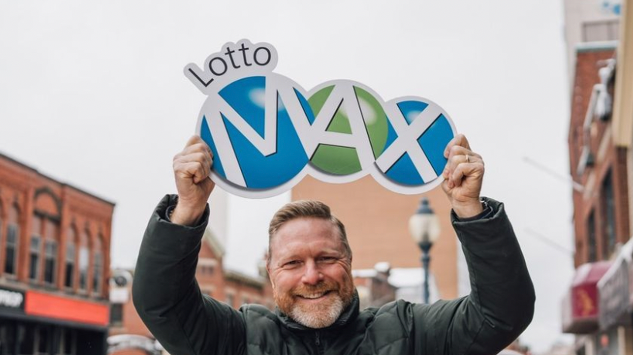 A person holding a Lotto Max sign.