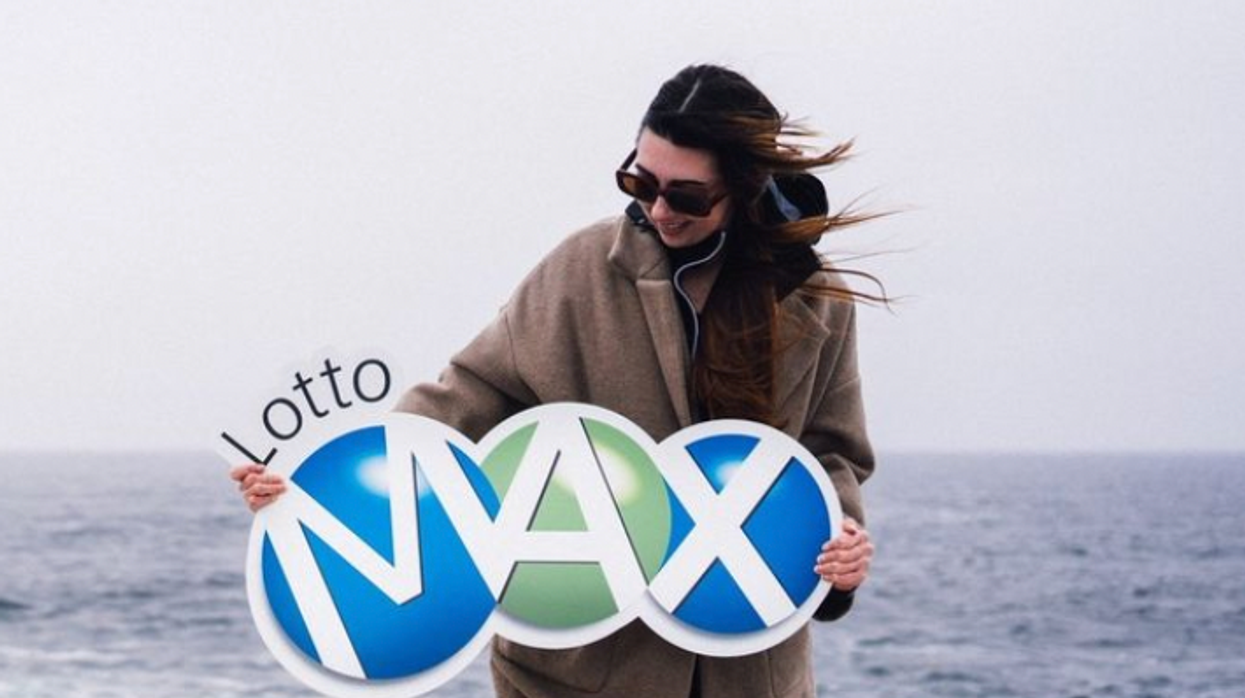 A person holding a Lotto Max sign.