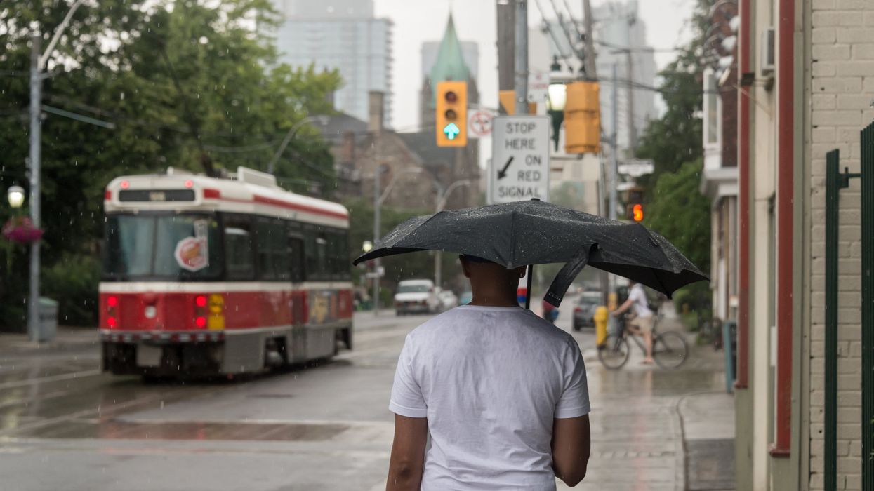 A person holding a umbrella as it rains in Toronto.