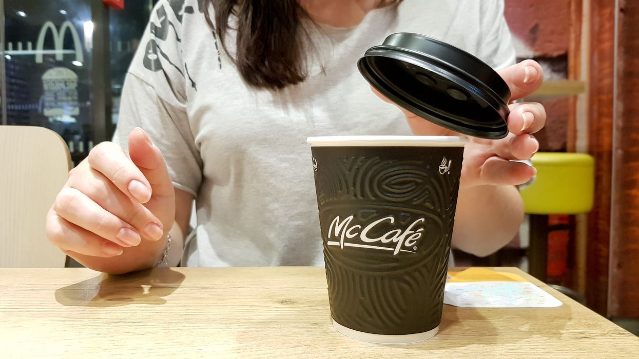 A person holding the lid of a McCafe drink.