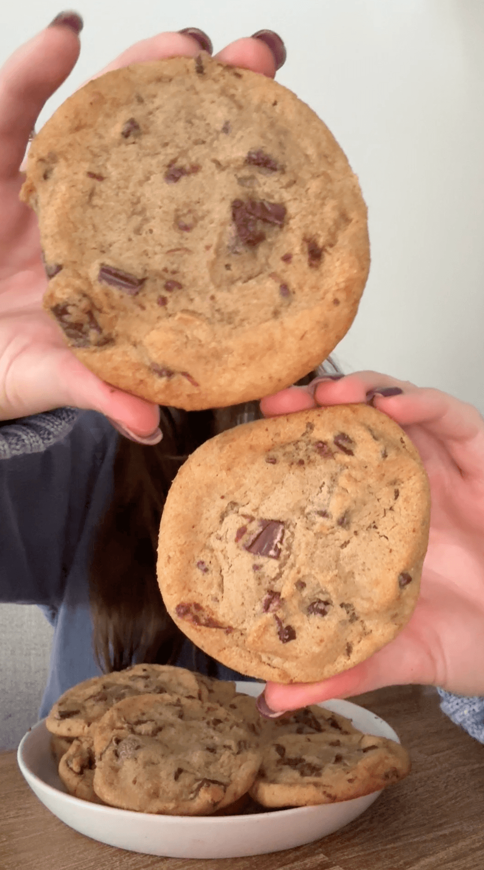 A person holding up two cookies.