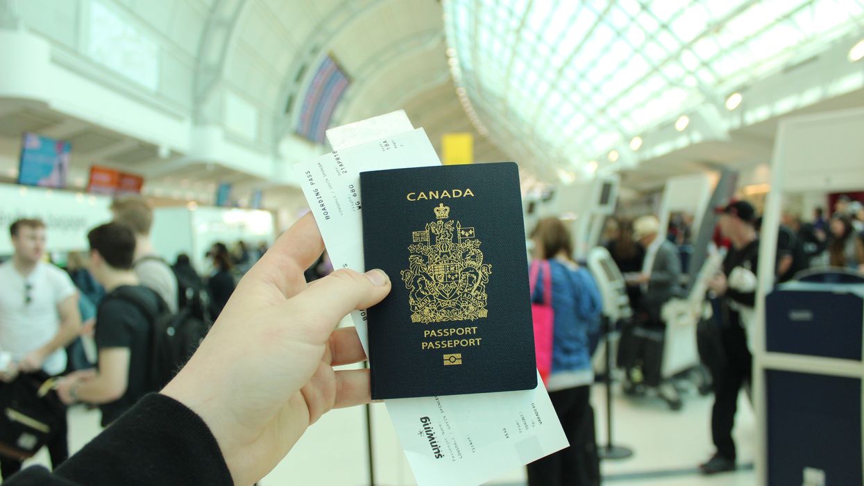 A person holds a Canadian passport in an airport.