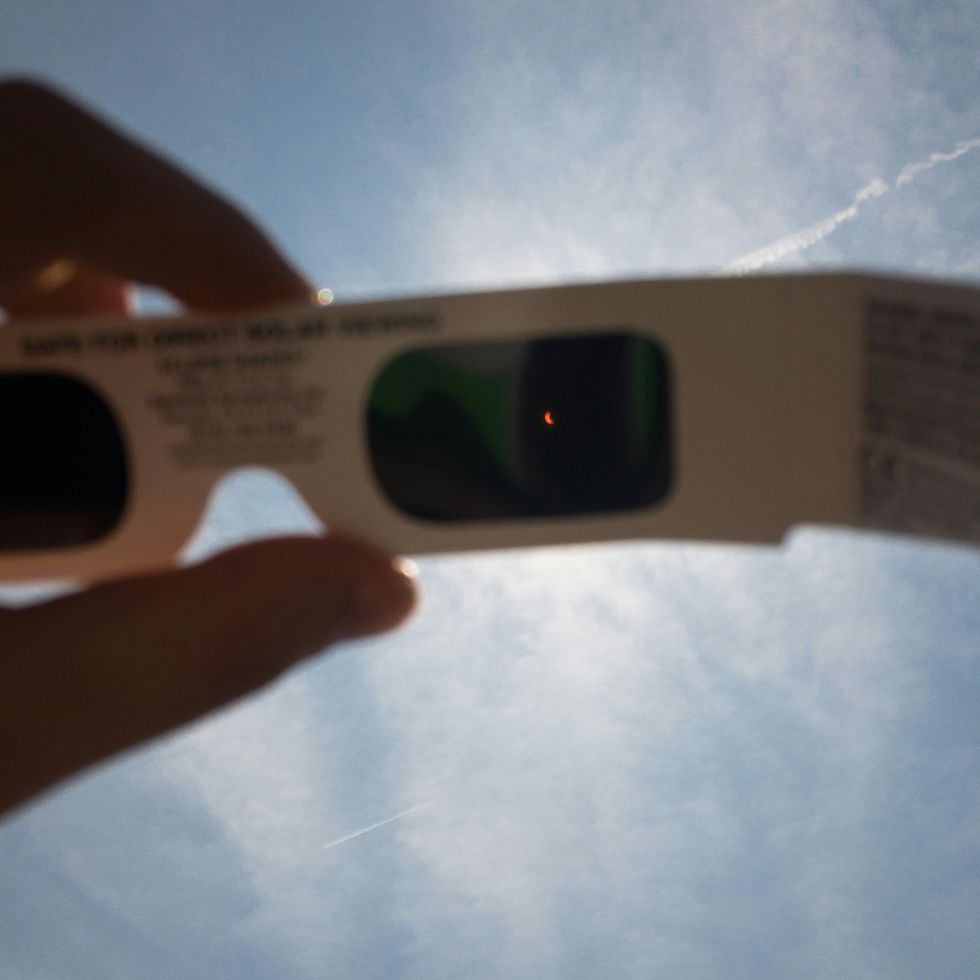 A person holds a pair of eclipse glasses.