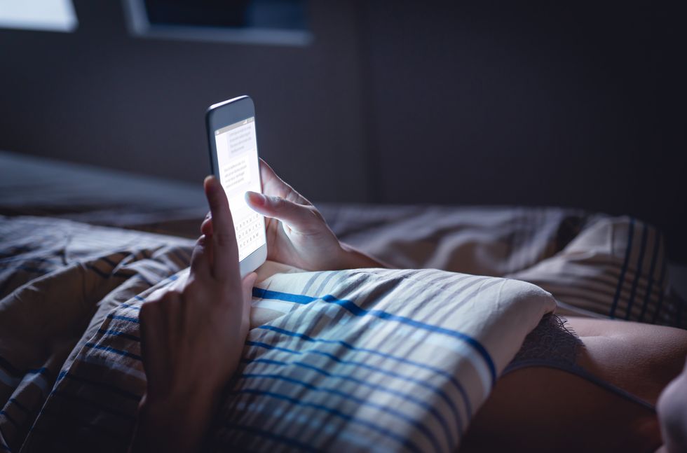 A person in their bed texting.