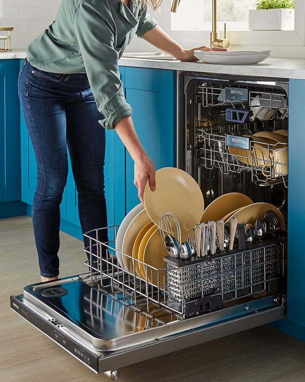 A person loads plates into a dishwasher.