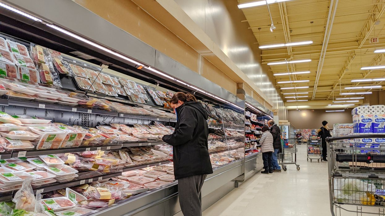 A person looking at meat in the grocery store.