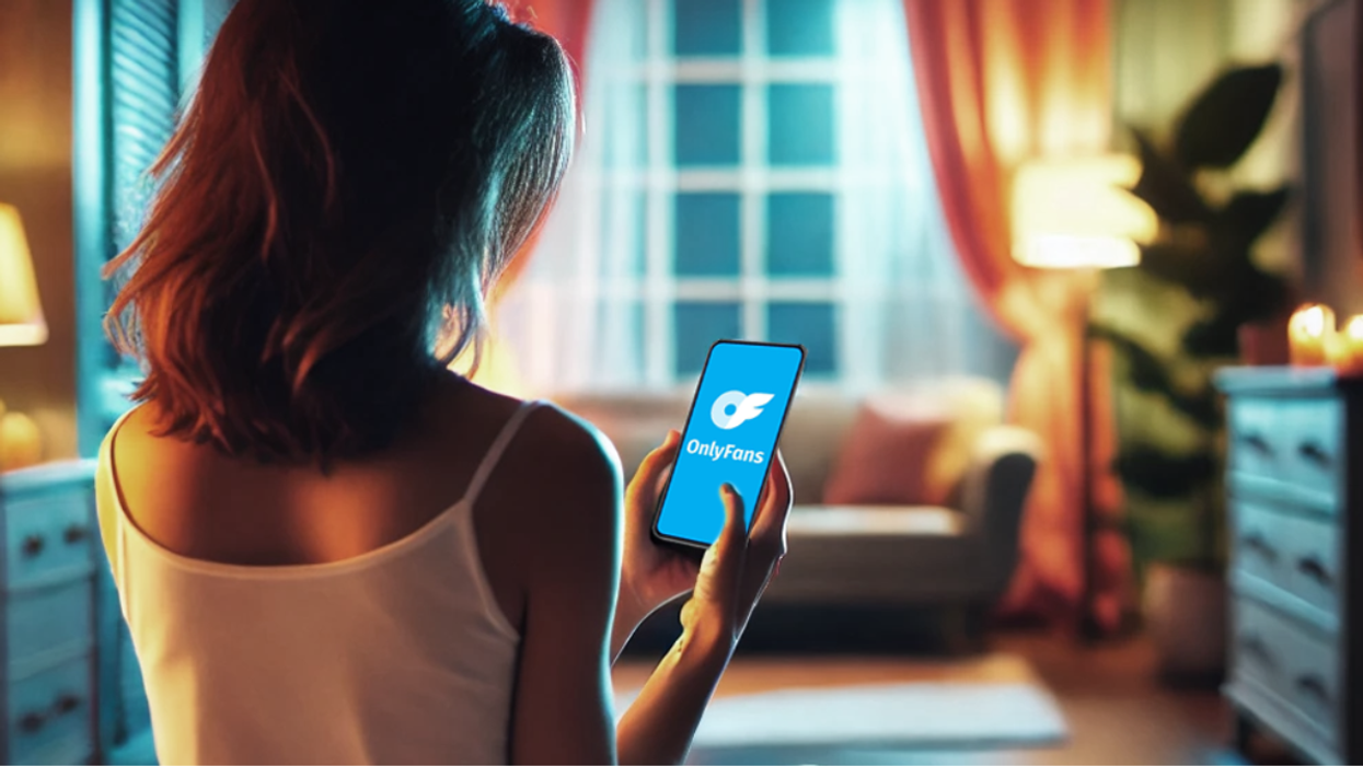 A person looks at the OnlyFans logo on a phone.