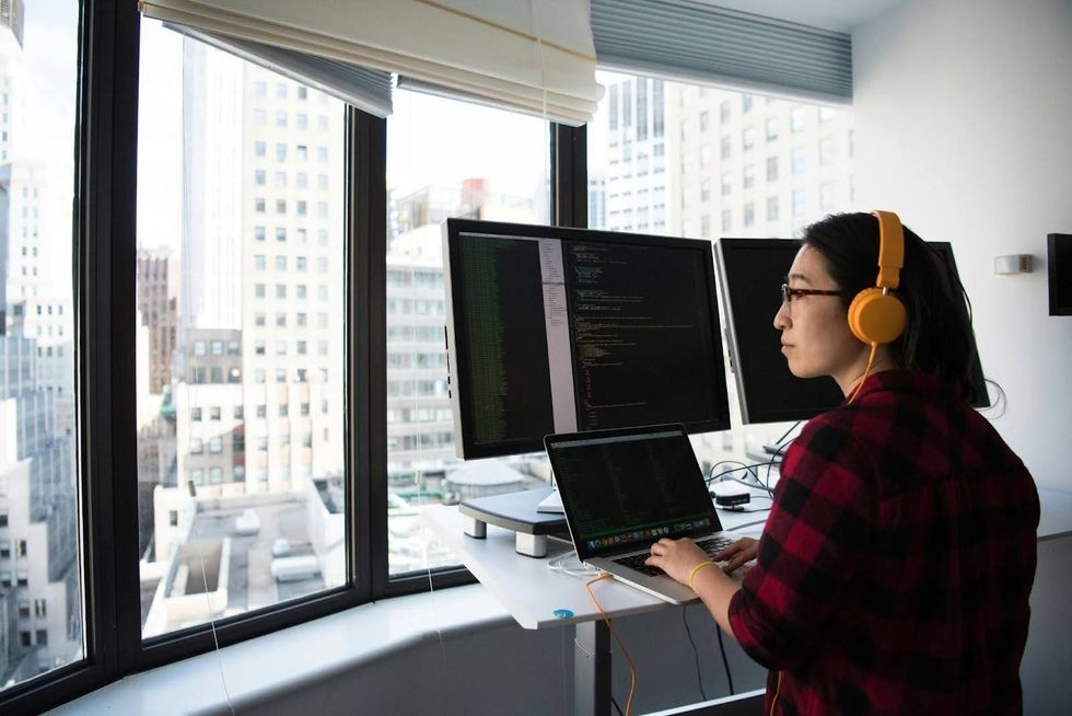 A person looks out the window while working at a standing desk. 