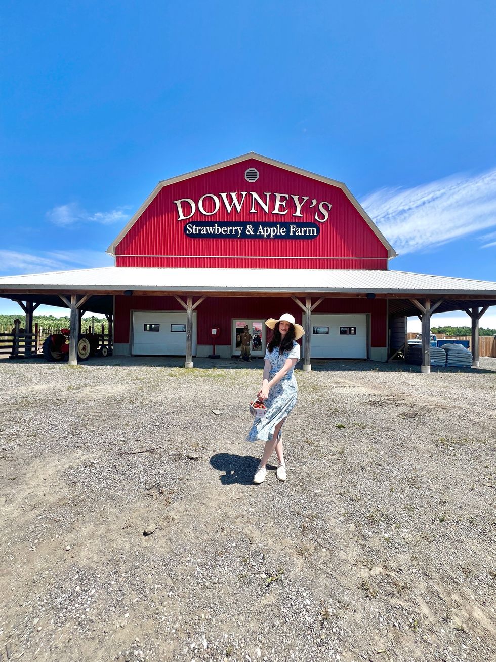 A person outside a red barn.
