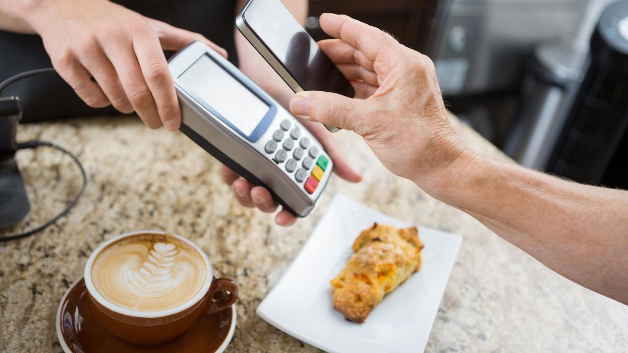 A person paying for their coffee and pastry in a cafe.