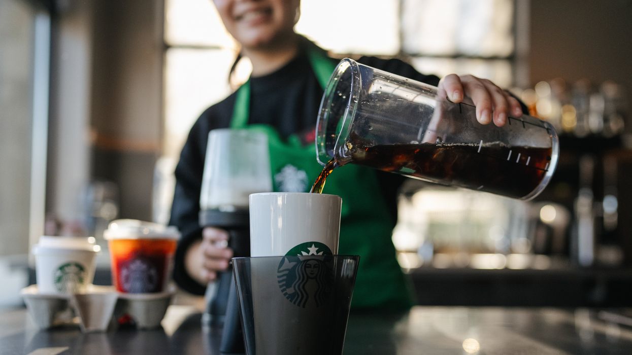 A person pouring coffee into a reusable mug.