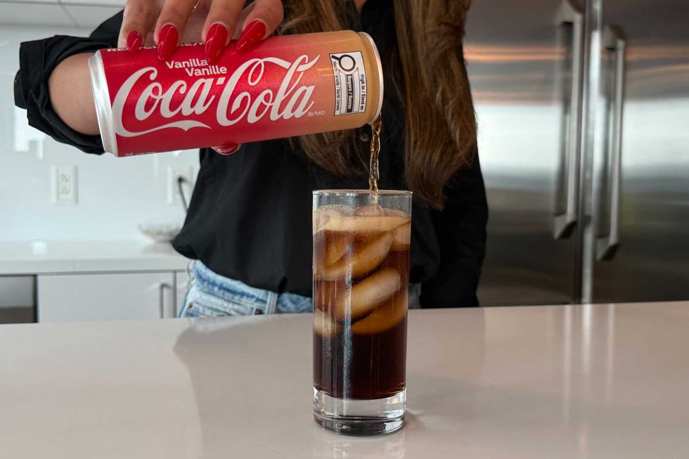 A person pours Coca-Cola Vanilla into a glass