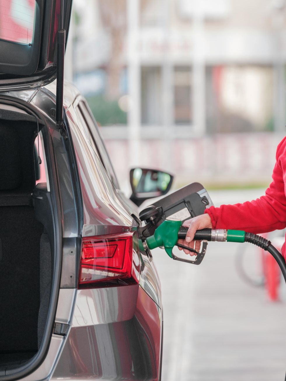 A person refuels their car at a gas station.