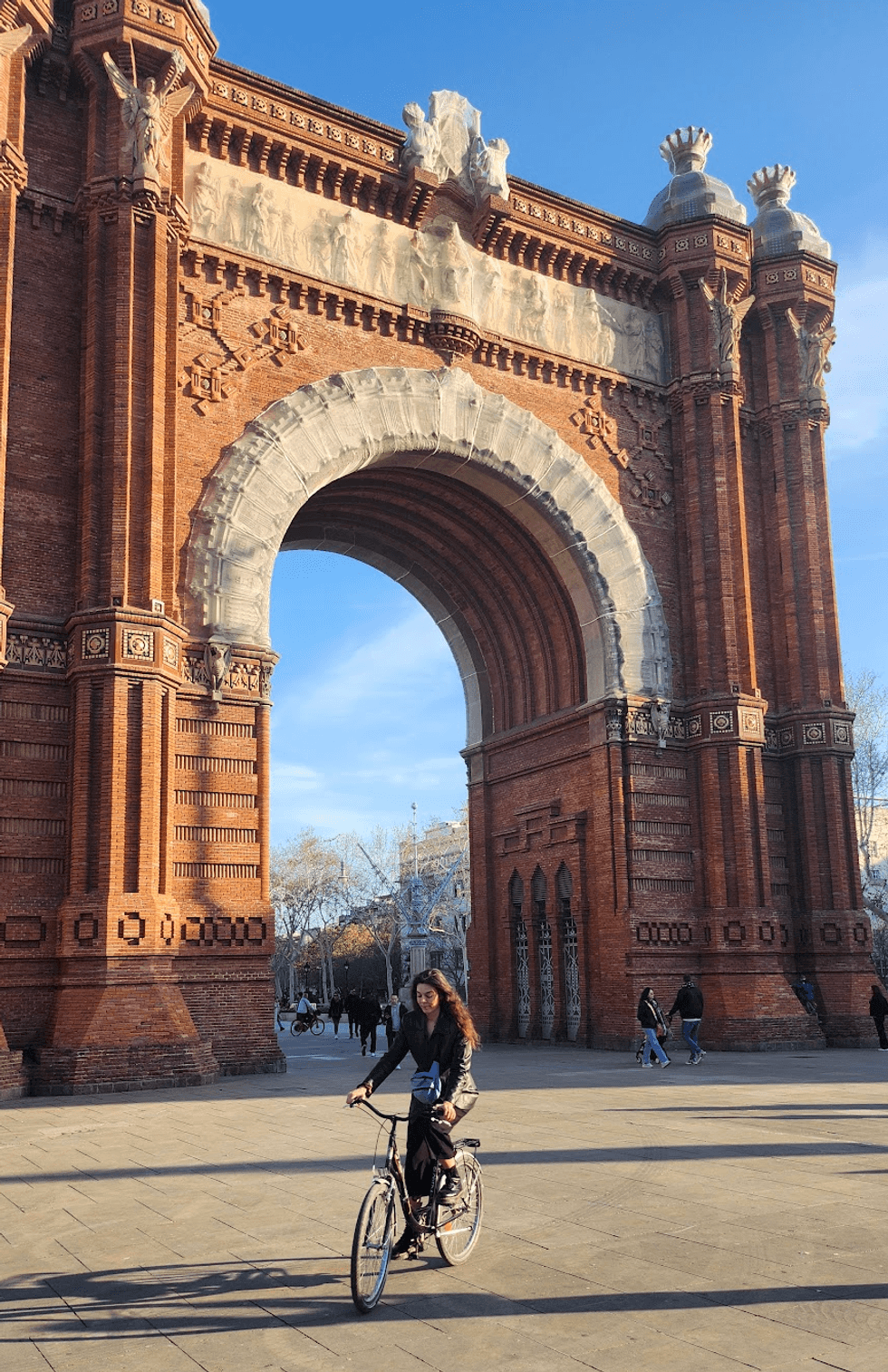 A person riding a bike under a large arch.