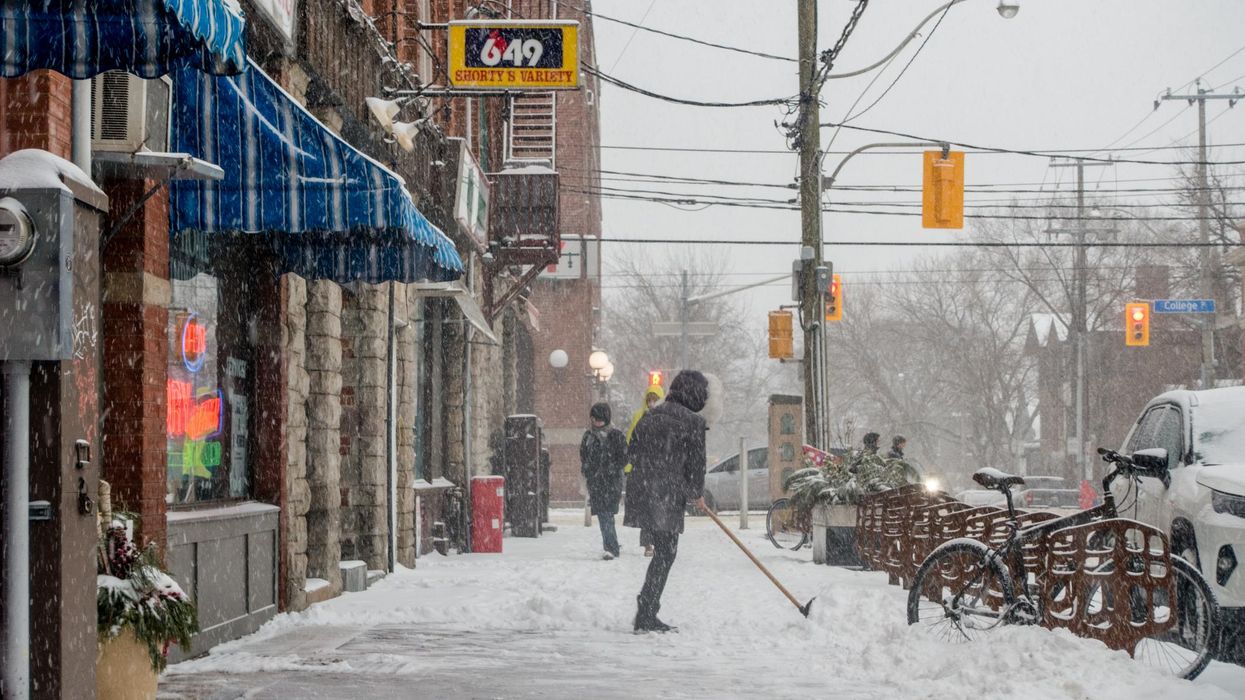 A person shovelling in Toronto during a snow storm.