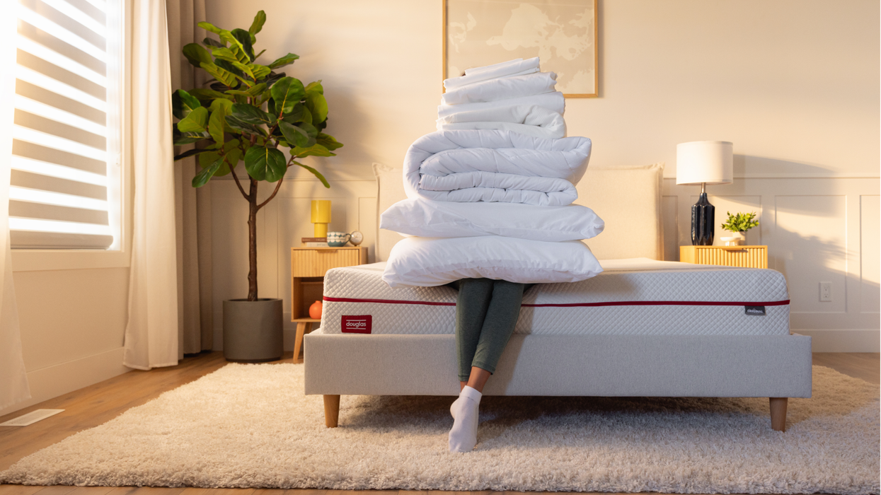 A person sitting on a bed with bedding on their lap.
