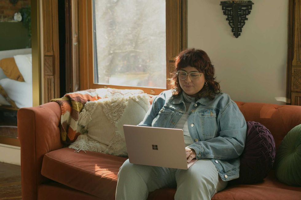A person sitting on a sofa with a laptop.