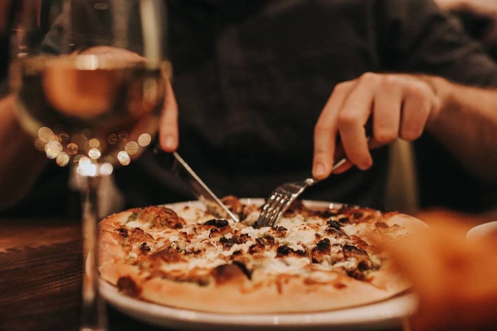 A person slices into a pizza at Banco Bistro.
