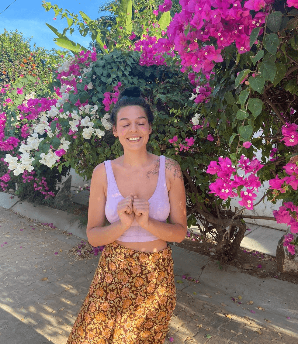 A person smiling next to a flower bush.