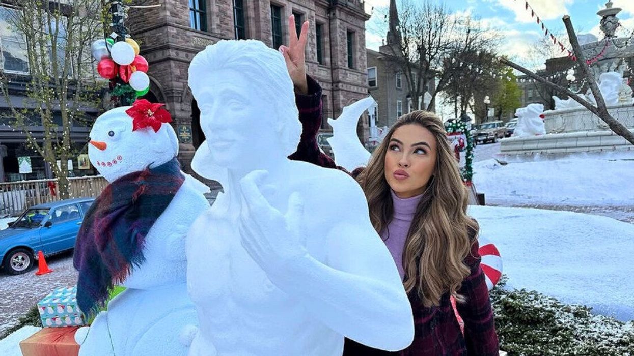 A person standing by a snow sculpture.