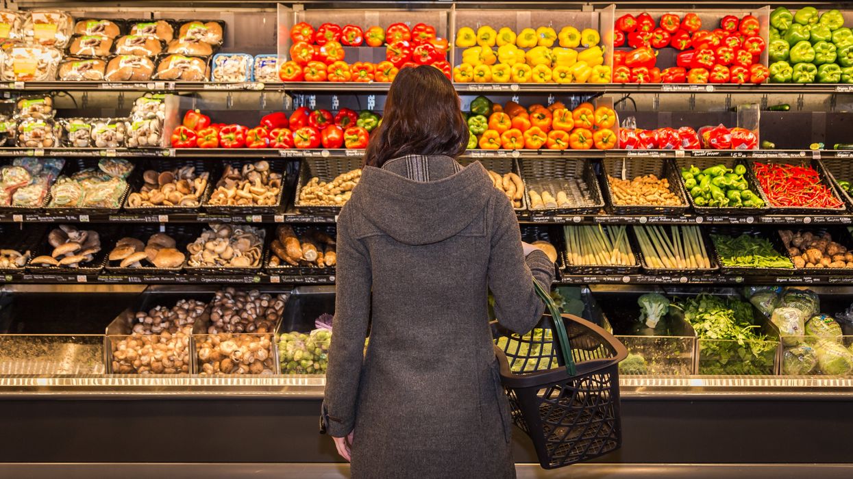 A person standing in front of produce at the grocery store.
