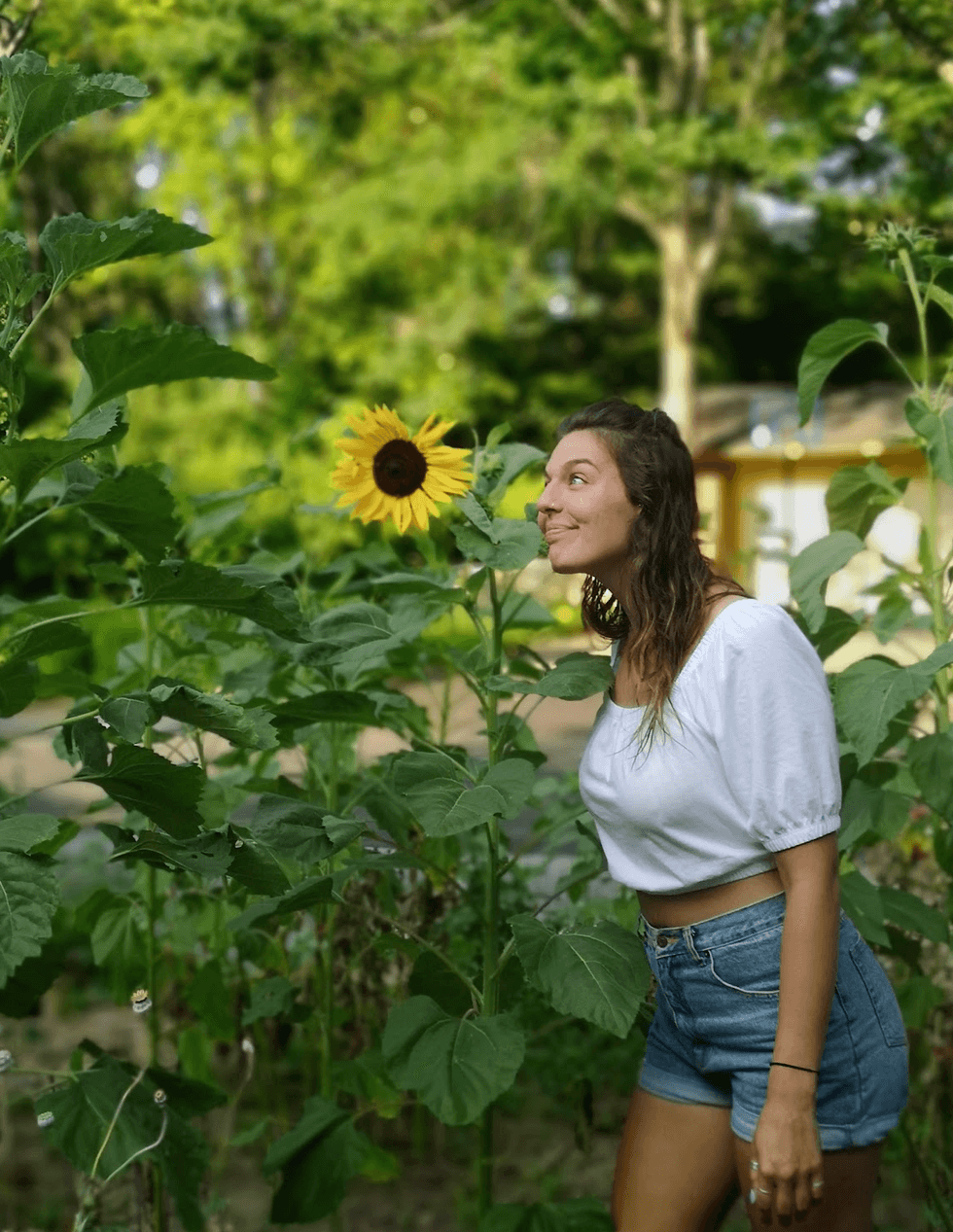 A person standing next to a sunflower.