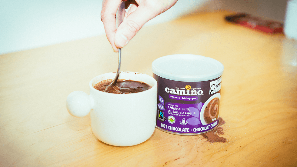 A person stirring a cup of Camino hot chocolate.
