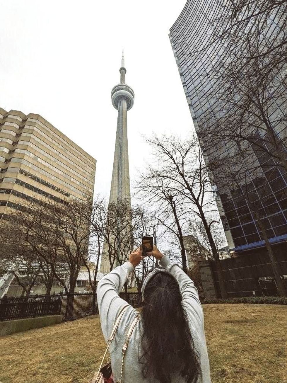 A person taking a picture of the CN Tower.