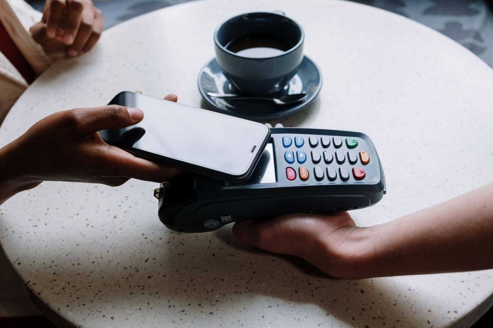 A person taps their phone against a POS terminal.