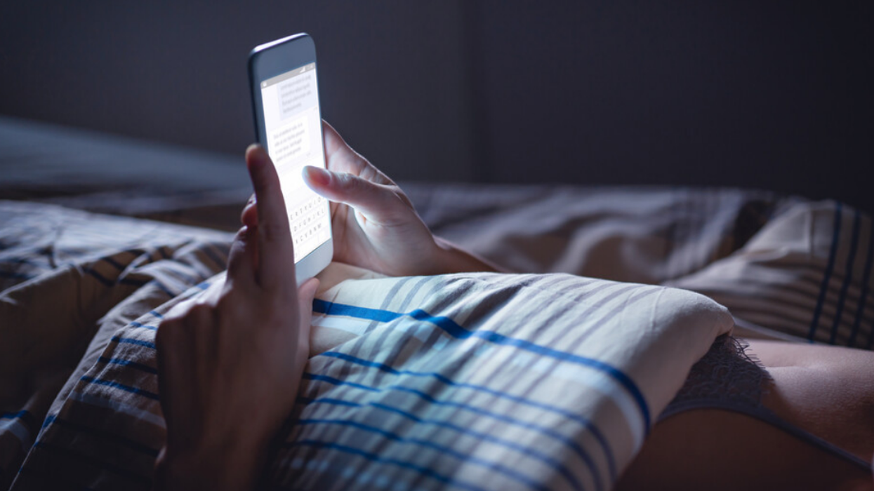 A person texting on their phone while in bed.