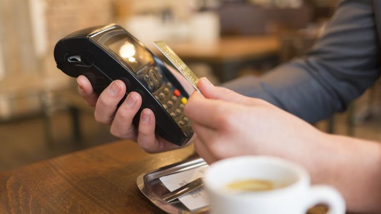 A person uses a credit card in a cafe.
