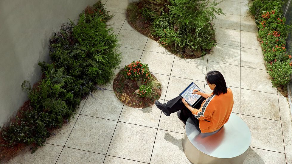 A person using the Galaxy Book4 Pro 360 in a sunny courtyard.