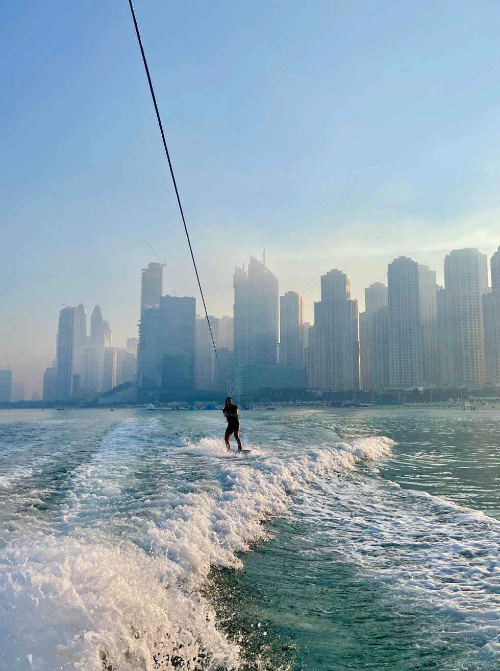 A person wakeboarding in Dubai with high-rise buildings behind her.