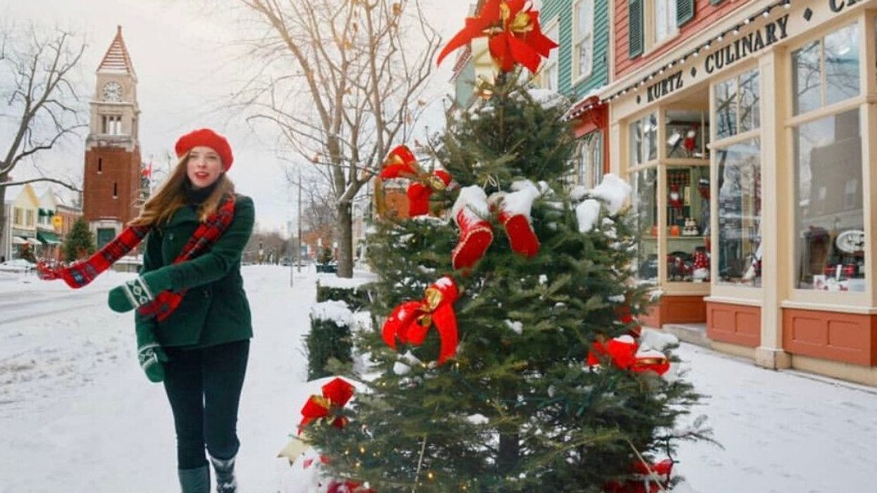 A person walking by Christmas decor in a small town.
