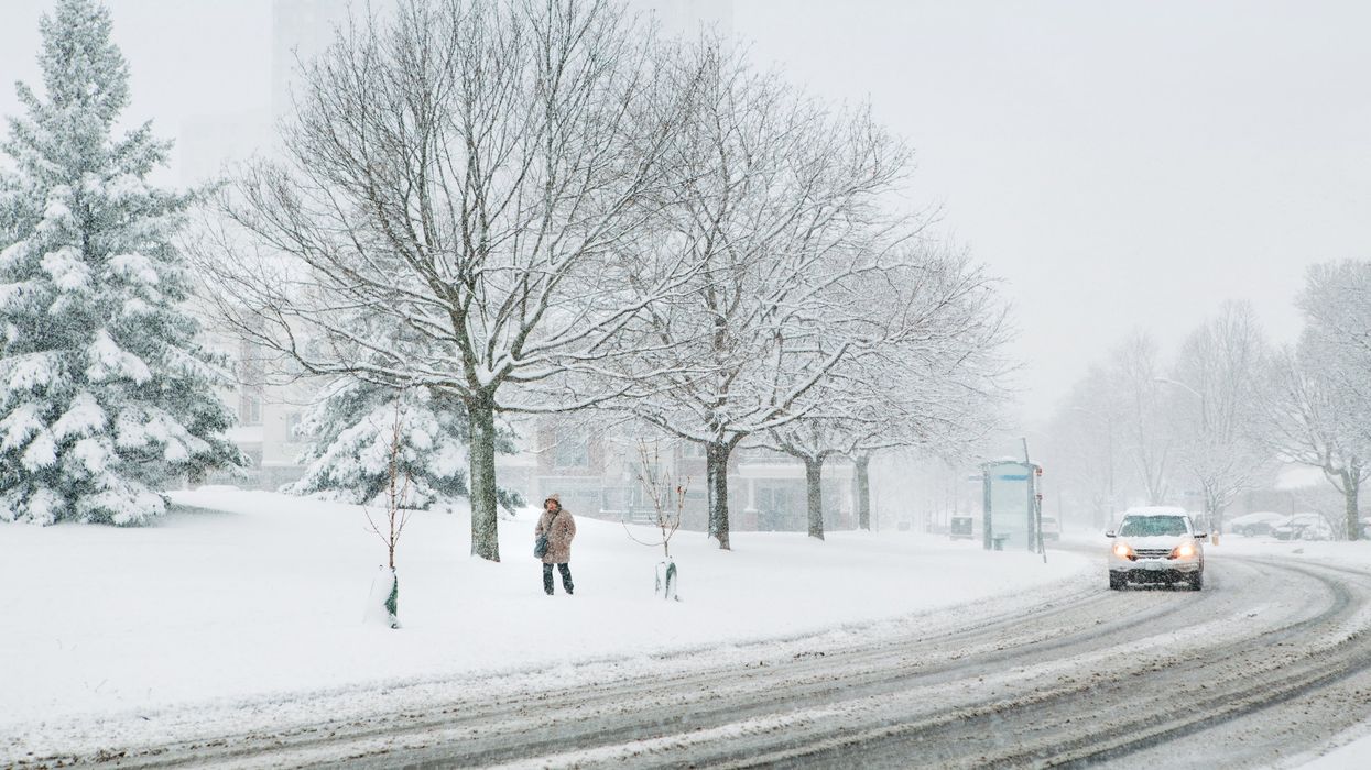 A person walks by the side of a road after a heavy snowfall.