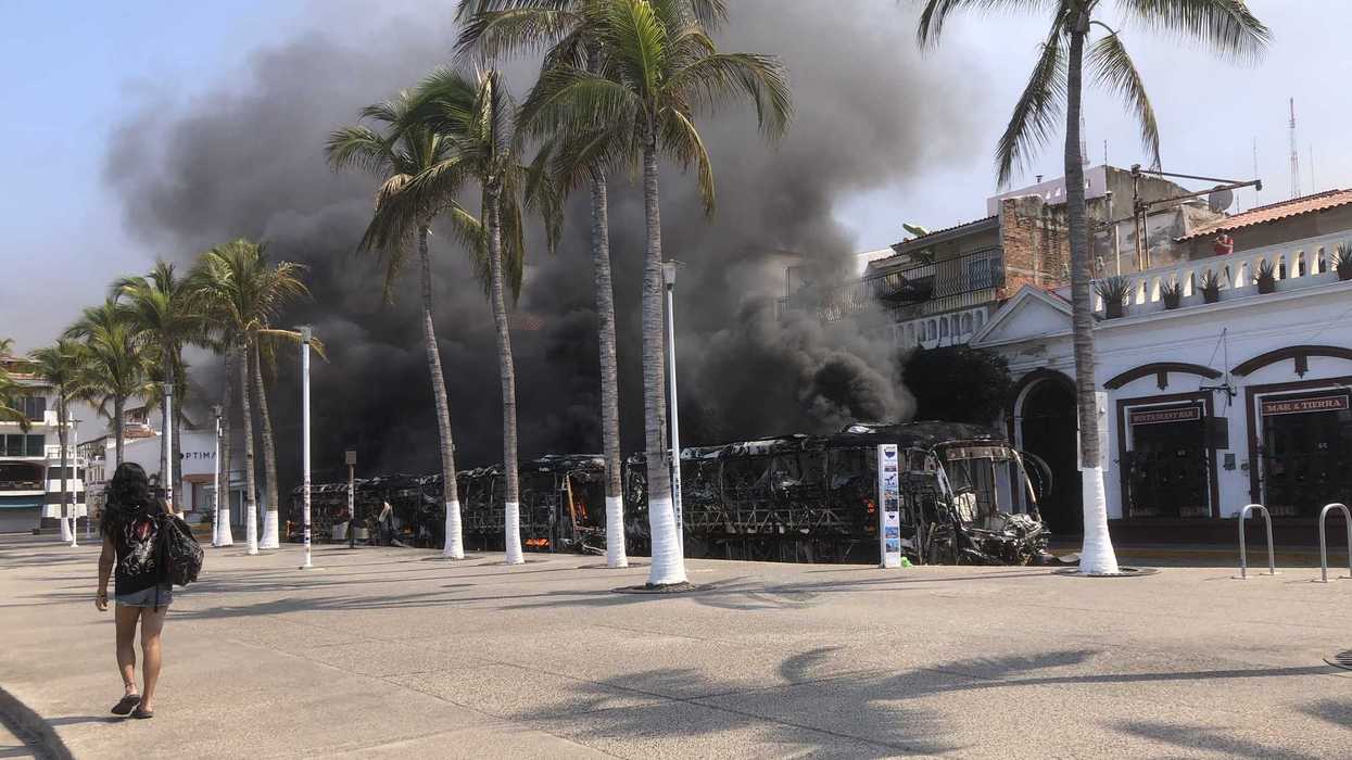 A person walks near a burned out bus on the boardwalk in the tourist area of Puerto Vallarta, Mexico.