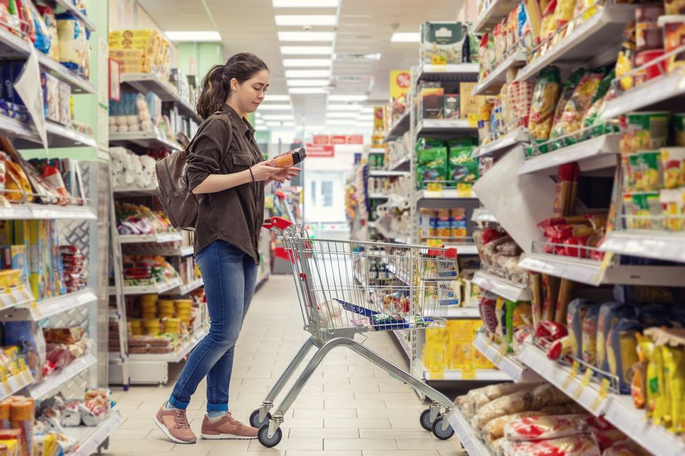 A person with a grocery cart chooses products at the grocery store.