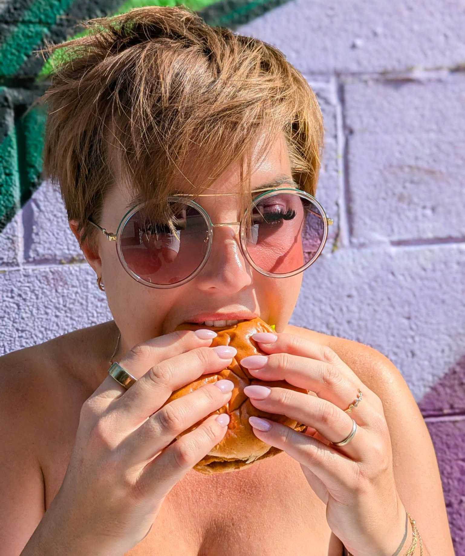 A photo of a person biting into a chicken burger