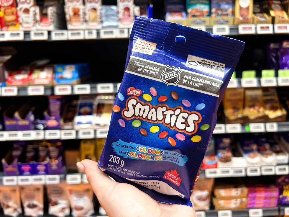 a photo of a person holding a bag of smarties in a candy aisle