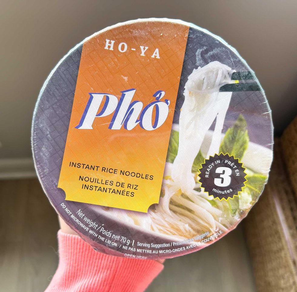 A photo of someone holding up a pho instant noodle bowl.