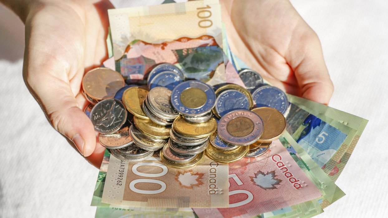 A pile of Canadian bills and coins in outstretched hands (illustrative).