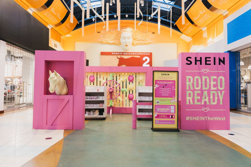 A pink display in the concours of a mall featuring make up, cowboy-themed decorations and a sign that reads "SHEIN Rodeo Ready #SHEINTheWest"