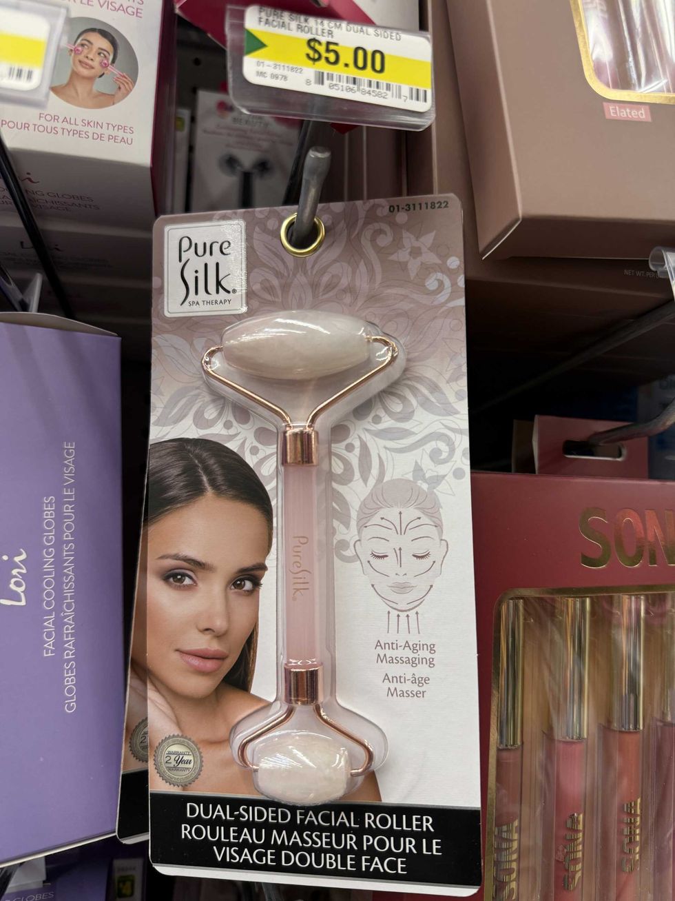A pink facial roller with a photo of a woman's face on it.